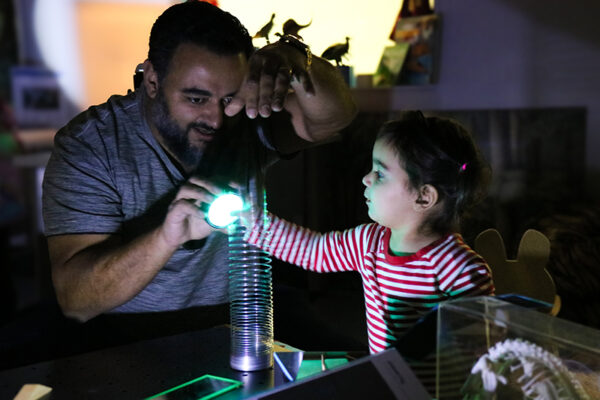 An adult and a child participate in an activity with light in the Dance Into the Light Pilot.