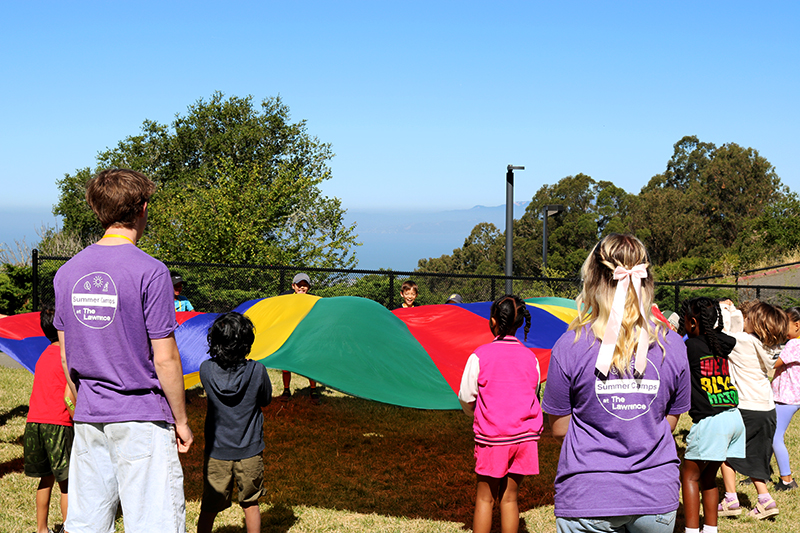 Camp teachers lead campers in a fun parachute activity