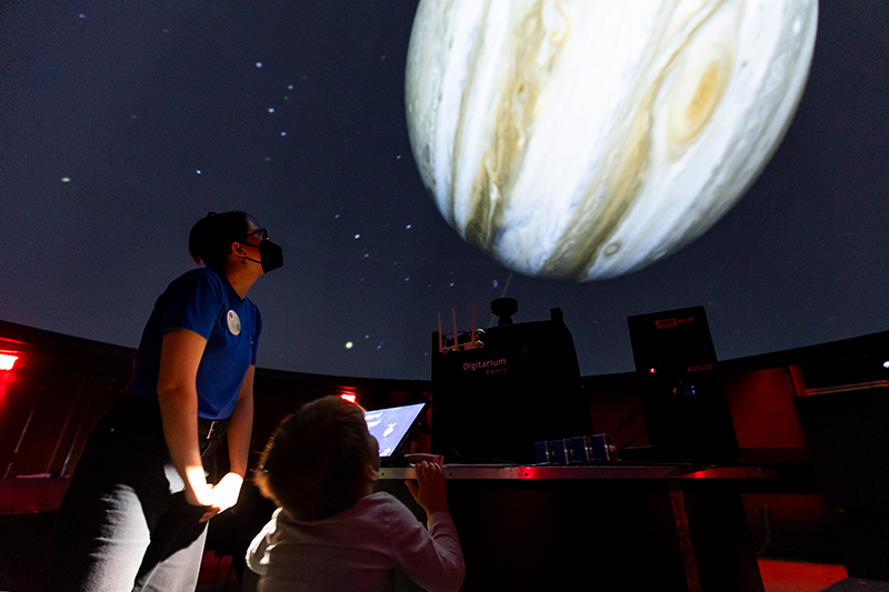 Planetarium Specialist Ellen Thompson observes Jupiter with a young visitor in Planetarium Pilots