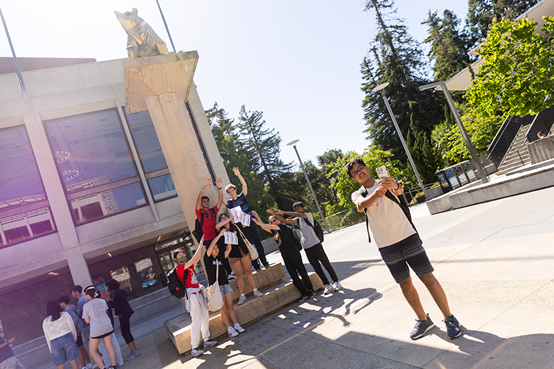 Teen Research Program participants take a selfie with a bear sculpture on campus