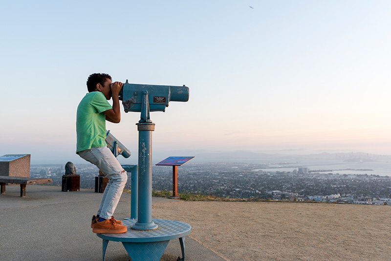 A vyoung visitor looking through a telescope at the view of the San Francisco Bay