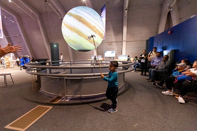 A visitor simulates the orbit of a spacecraft around Jupiter in a Science On a Sphere guided show