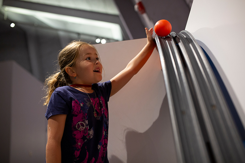 A visitor prepares to launch a ball down the gravity tracks in the Young Explorers Area