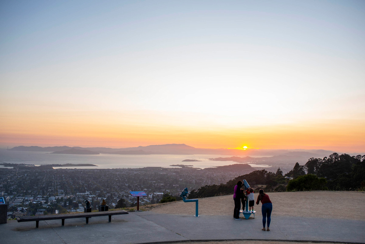 Visitors look through the telescopes during sunset at the view of the bay from The Lawrence.