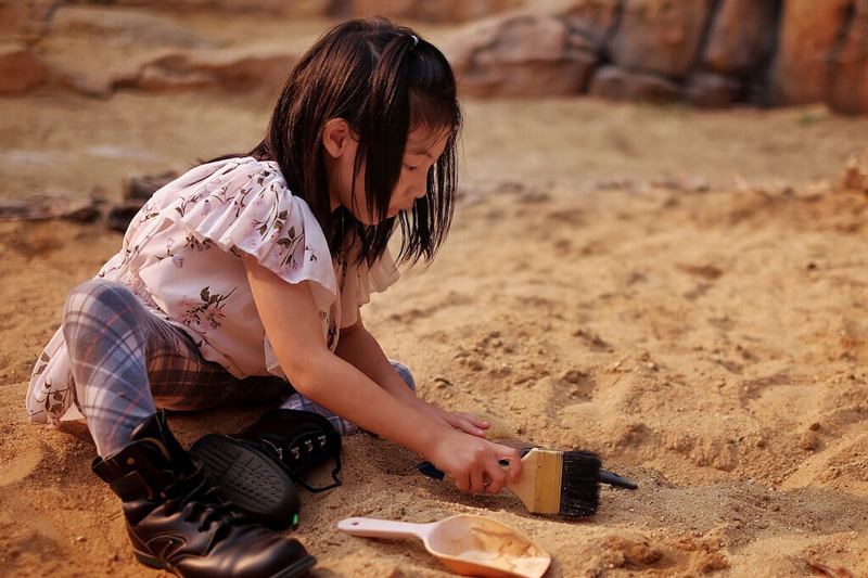 A young child digs for dinosaur fossils