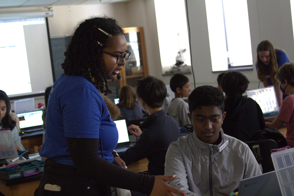 An instructor helping a student code a nanosatellite.