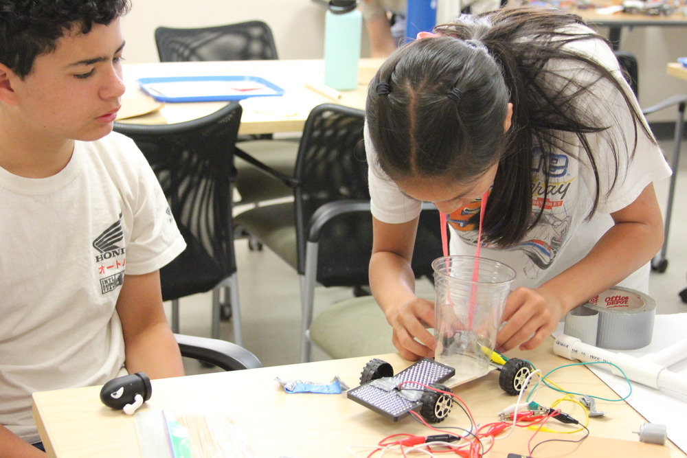 Two teens working on a solar car.