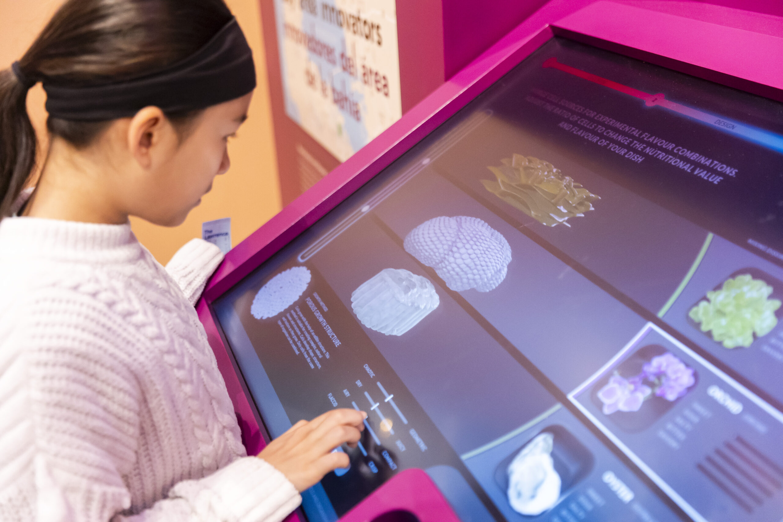 A child interacts with an interactive digital display at a science exhibit, exploring various biological specimens shown on the screen.