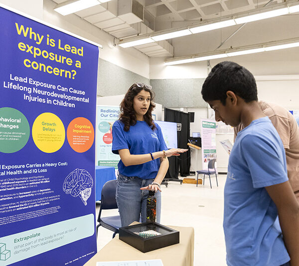 A high school student shares their research on lead contamination with Lawrence visitors on STEM Day