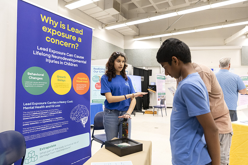 A high school student shares their research on lead contamination with Lawrence visitors on STEM Day