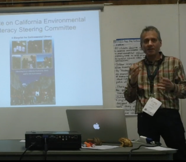 Craig Strang stands in front of a powerpoint presentation.