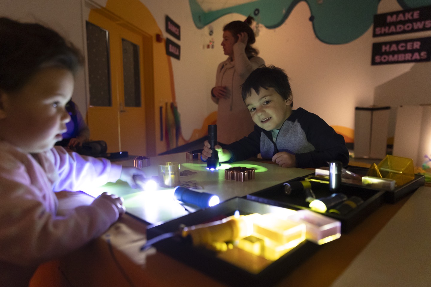 Young boy sorting through colorful translucent toys and building blocks at an illuminated play station during the Glowtastic exhibit