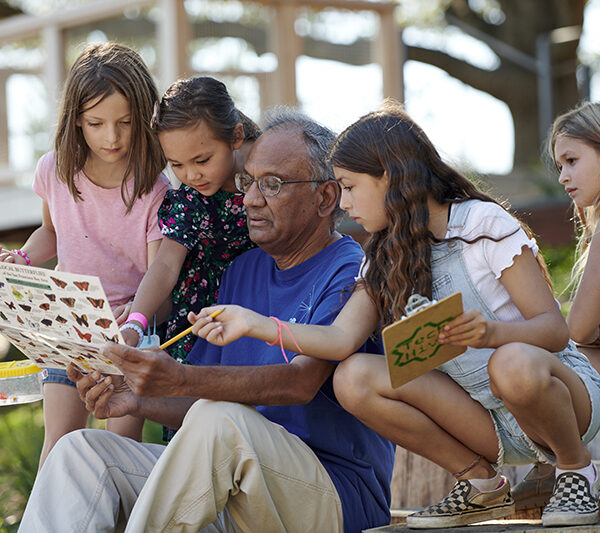 A Lawrence volunteer shows young visitors a butterfly identification guide in the Outdoor Nature Lab