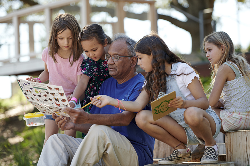 A Lawrence volunteer shows young visitors a butterfly identification guide in the Outdoor Nature Lab