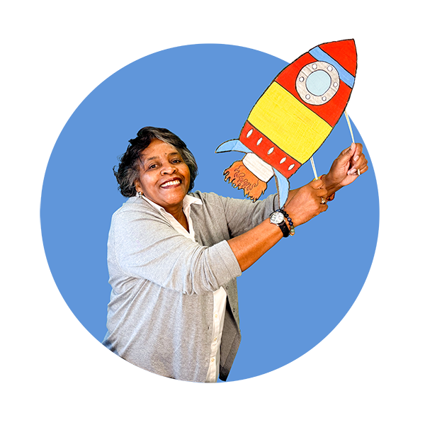 Community Science Hero Janet Barnes, holding a paper rocket ship crafted by one of her students