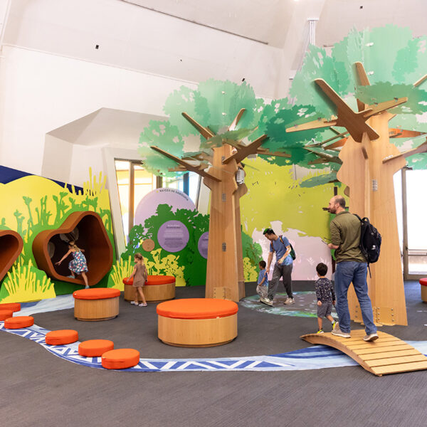 Visitors explore the yuutka exhibit, featuring three large tree-like structures, two reading nooks, and other elements.