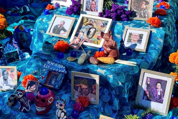A vibrant altar adorned with framed photographs, colorful marigolds, sugar skulls, and traditional decorations, honoring loved ones during the Day of the Dead.